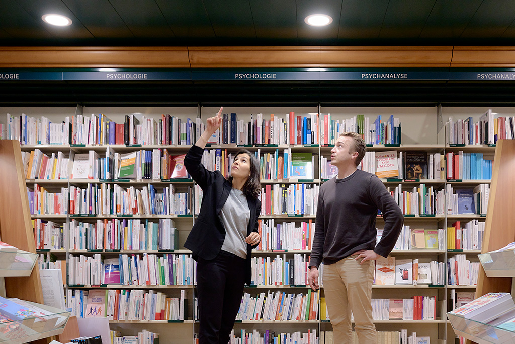Deux personnes constatent l'éclairage écologique conseillé par equiwatt dans sa bibliothèque